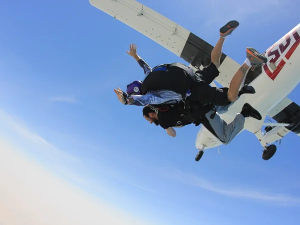 Two tandem skydivers in freefall seconds after leaving the aircraft, the plane still above them